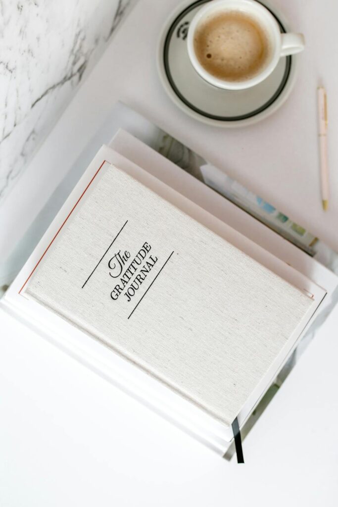 Gratitude journal and coffee cup on a soft-toned desk styled for a mindful luxury wedding planner workspace
