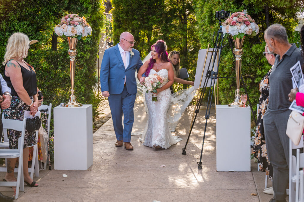 Bride walking down the aisle with father while planner adjusts her veil – Marshecka Weddings luxury ceremony moment