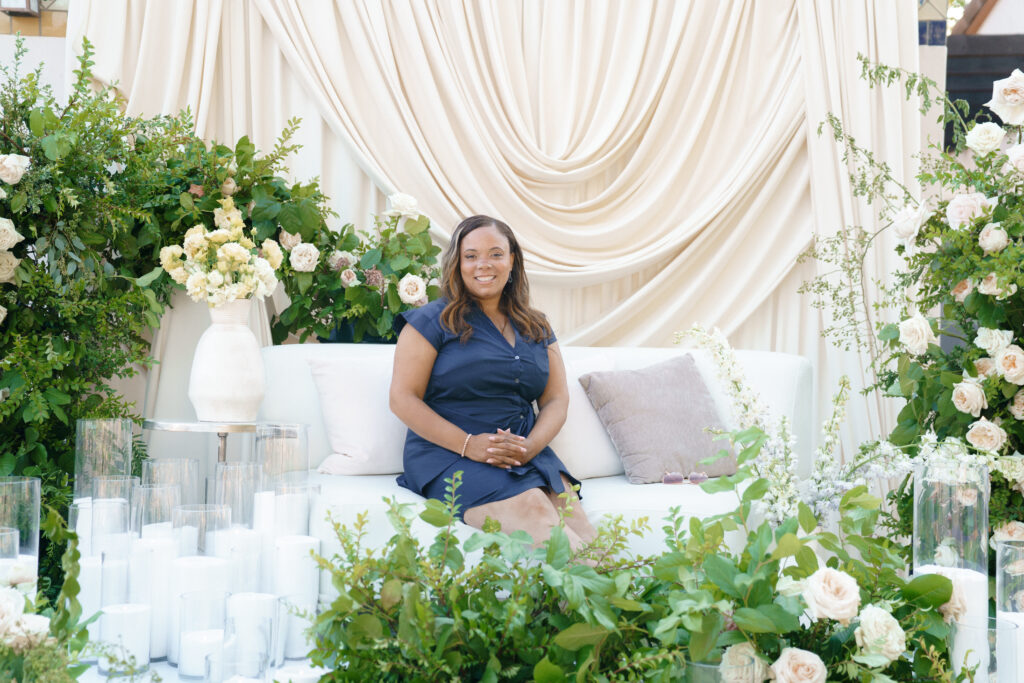 Luxury wedding planner Marshecka seated in an elegant editorial wedding design setting with soft draping, candles, and lush florals