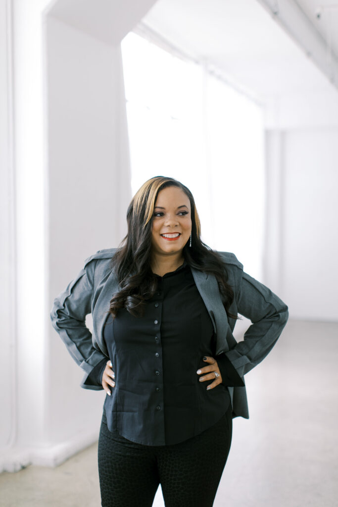 Luxury wedding planner Marshecka standing in a bright studio setting holding a coffee mug, reflecting a warm and personalized client experience.